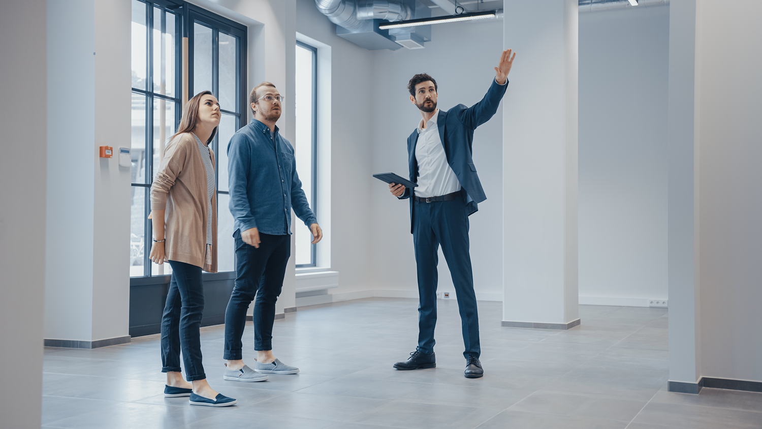 Tenant rep broker shows commercial real estate office space to a prospective tenant.